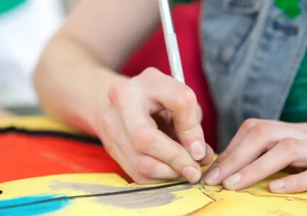 Artist working with colorful material and a utensil of some sort