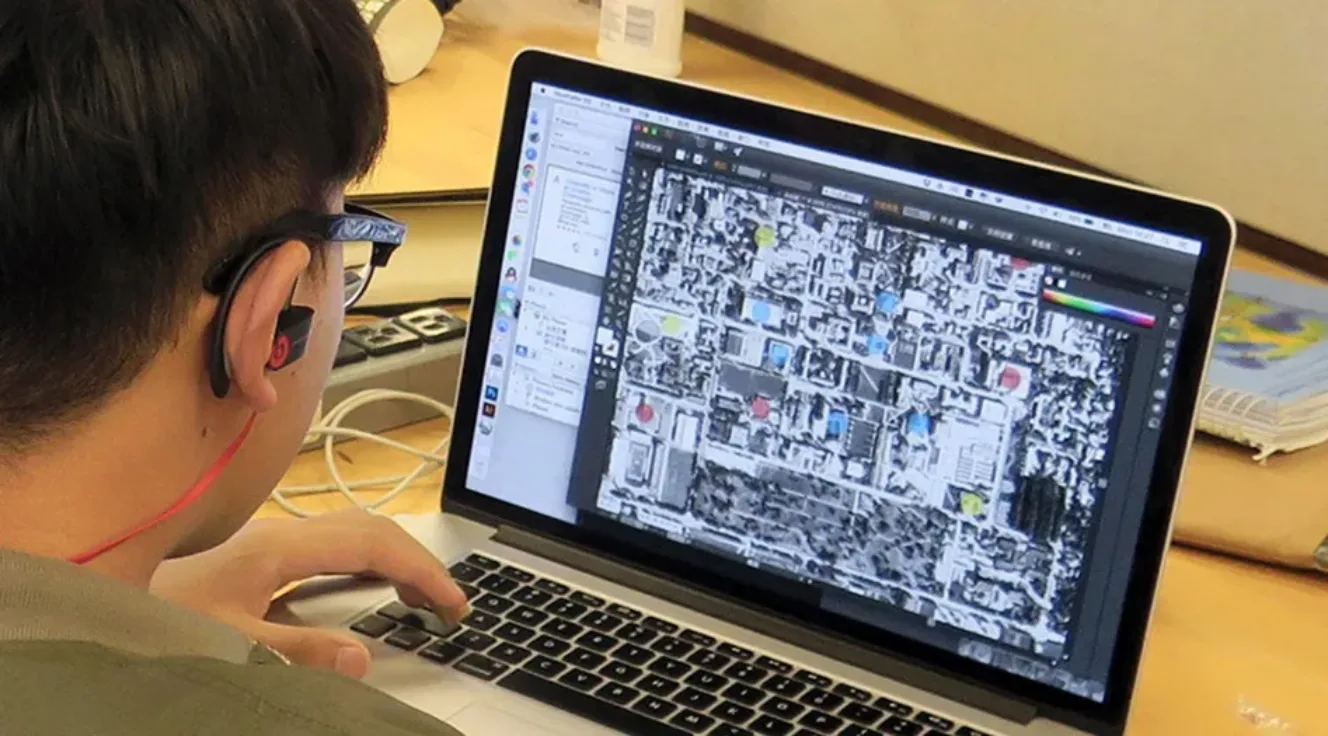 Student working on a laptop computer to adapt a satellite view of a community