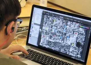 Student working on a laptop computer to adapt a satellite view of a community