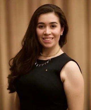 Facilities and Operations Coordinator, Miranda C. Molina, wearing black pleated A-line Calvin Klein dress and a gold plated necklace.