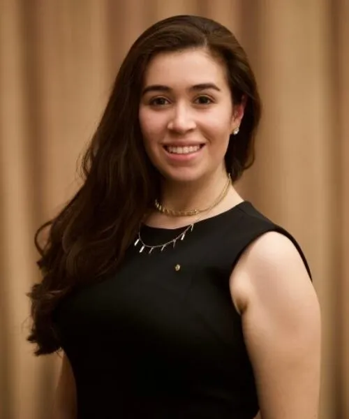 Facilities and Operations Coordinator, Miranda C. Molina, wearing black pleated A-line Calvin Klein dress and a gold plated necklace.