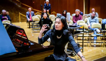 person sitting at piano gestures with their hands while talking