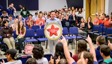 Marching Illini director Barry Houser announces to band members that they will perform in the 100th Macy’s Thanksgiving Day Parade in 2026, one of 10 marching bands selected from more than 100 applicants. The band assembled at the Harding Band Building to hear the historic news. This will be Marching Illini’s second appearance in the parade, with the first being in 2015. Photo by Fred Zwicky