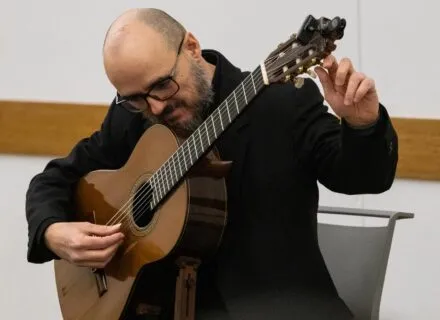 Dr. Guido Sánchez Portuguez, assistant professor in FAA, tunes his acoustic guitar during his concert performance at the Champaign Public Library on Jan. 30.  Photo by Sarah Slattery, The Daily Illini