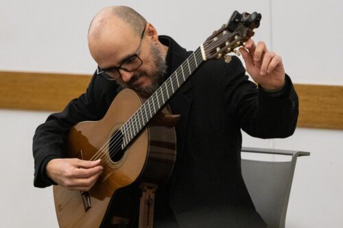 Dr. Guido Sánchez Portuguez, assistant professor in FAA, tunes his acoustic guitar during his concert performance at the Champaign Public Library on Jan. 30.  Photo by Sarah Slattery, The Daily Illini