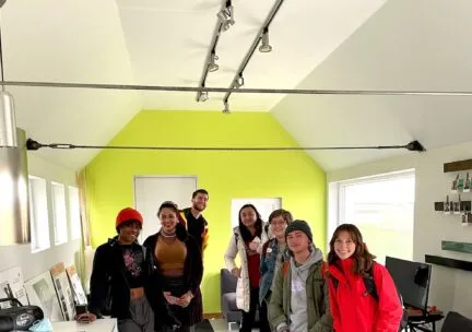 several architecture students stand in room with light green wall in back