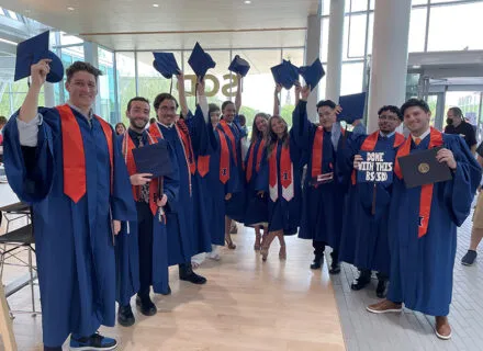 BSSD students stand in hald circle dressed in blue and orange graduation regalia