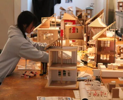 architecture student works on models in studio