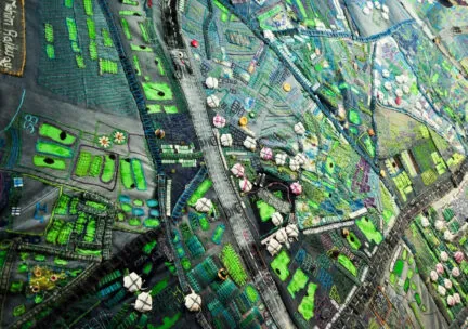 a city blueprint or outline in greens and blues made out of jeans and other found objects