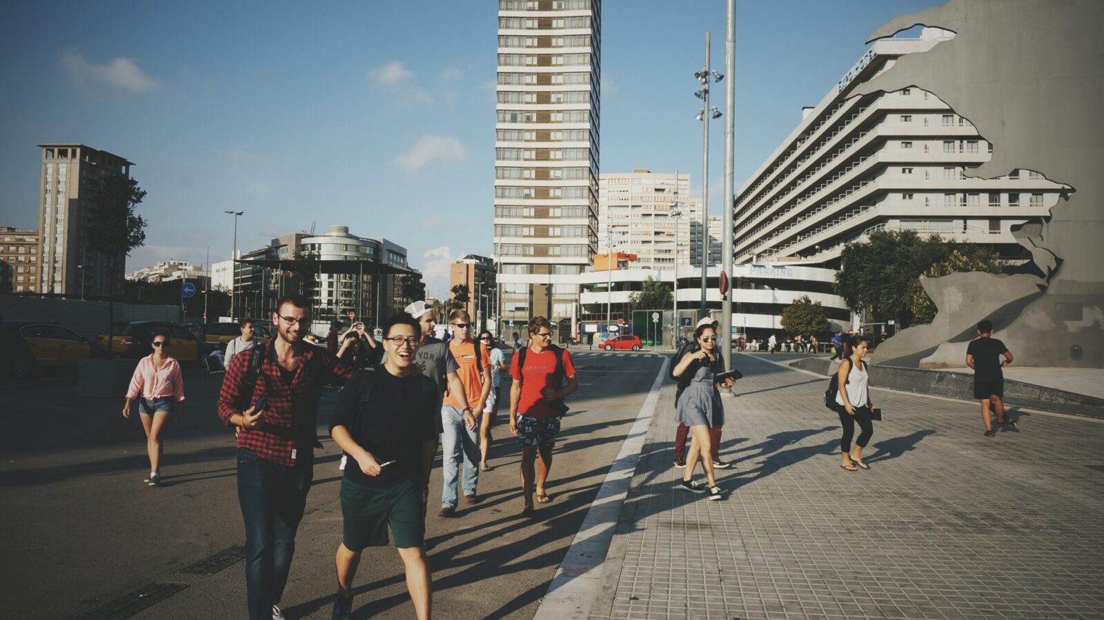 students scattered walking across a street with architecture in the background and blue skies