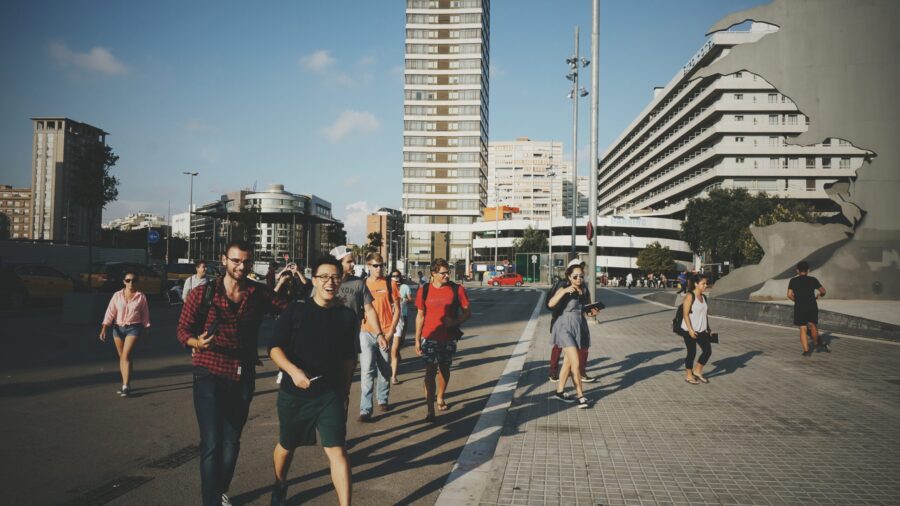 students scattered walking across a street with architecture in the background and blue skies