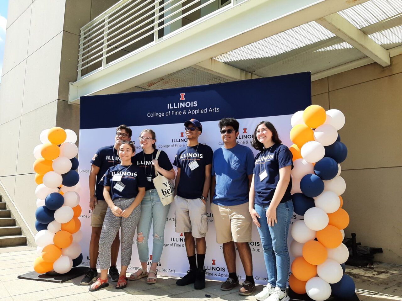 FAA students in front of step and repeat sign with orange and blue balloons