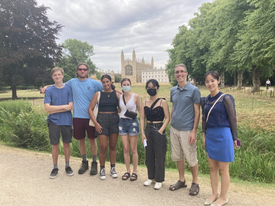 7 people standing in a line with a castle structure in the background