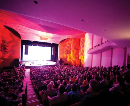 Krannert Center Festival Theatre from the back of the house lit up in reds and pinks with a full audience