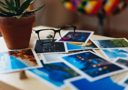 printed out photos of various landscapes with glasses and a plant