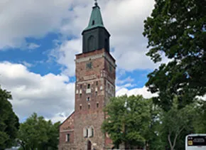 3 students' backs and a tall steeple