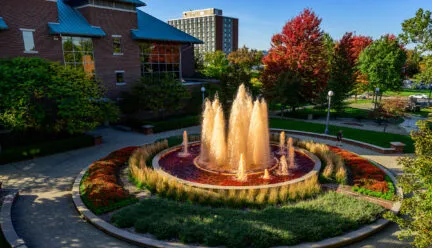 fountain showing orange water and colorful plants and flowers surrounding it