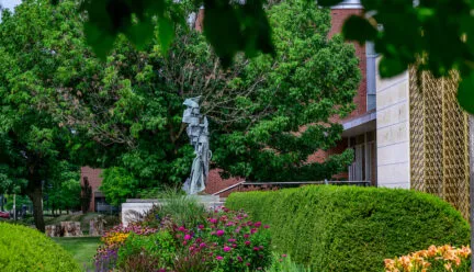 gardens outside KAM with lots of green shrubs and bright colorful flowers surrounding a green/gray statue