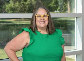 Person smiling with yellow glasses and green shirt
