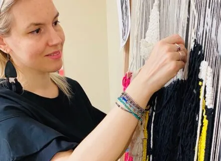 person working on textile hanging on wall