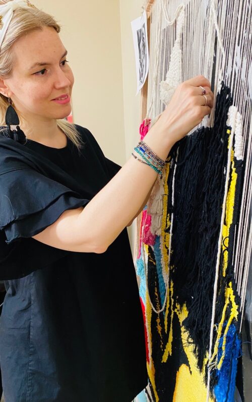 person working on textile hanging on wall