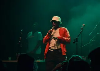 person singing into mic on a dark stage