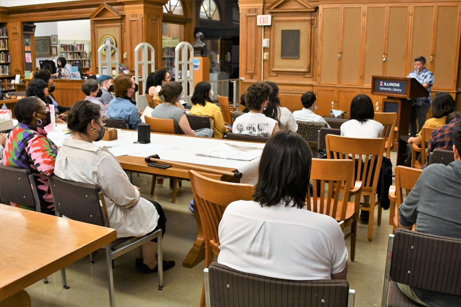 many people sitting in seats in library watching the speaker at the front podium