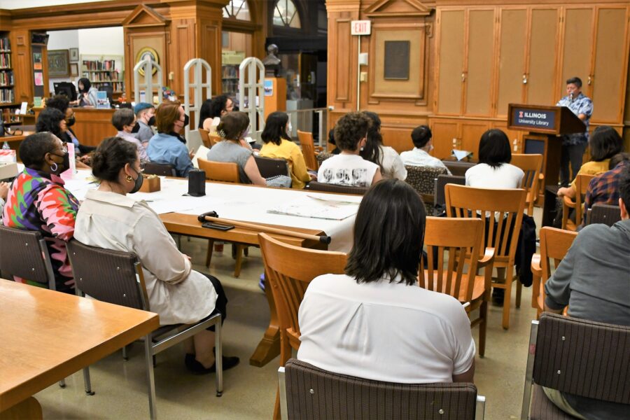 many people sitting in seats in library watching the speaker at the front podium