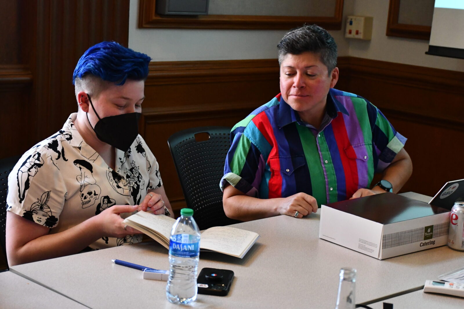 2 people sitting and sharing a book