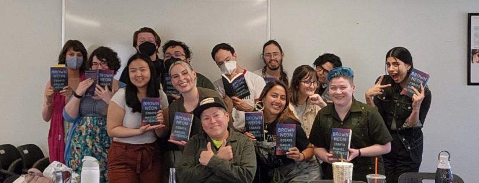 group of people holding up books and smiling