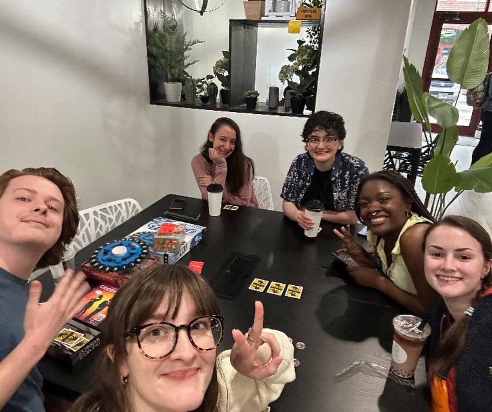 cast and crew gather around table with games and drinks