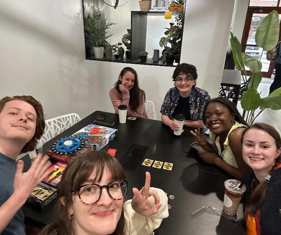 cast and crew gather around table with games and drinks