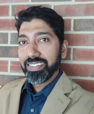 Photo of Prof. Arnab Chakraborty standing in front of a brick wall