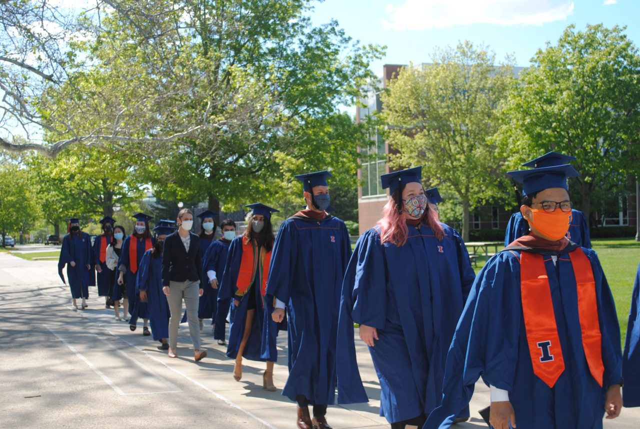 Students in cap and gown parading on quad