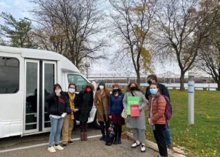 Students standing next to rental van by a bridge crossing the Illinois River