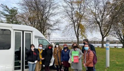 Students standing next to rental van by a bridge crossing the Illinois River