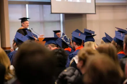 Graduates listening to department head during convocation ceremony