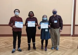 Photo of four graduate student winners of GIS poster competition in meeting room