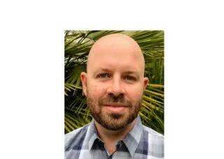 Photo of Dr. Kennedy in front of a green palm tree.