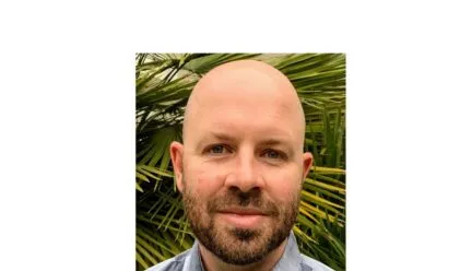 Photo of Dr. Kennedy in front of a green palm tree.