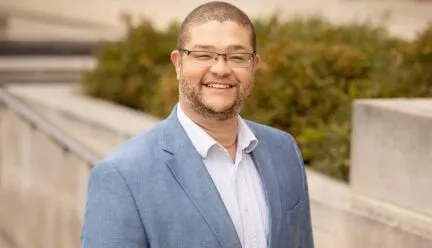 Photo of Dr. Andrew Greenlee outside in front of a concrete walkway in blue sports coat