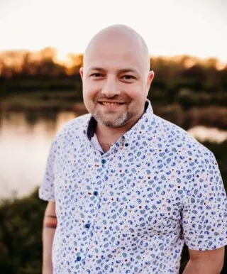 Photo of Evan Van Buskirk outside at sunset in front of a lake