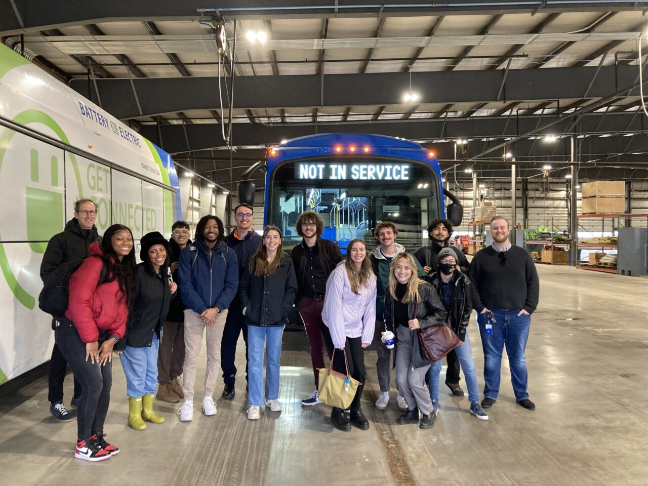 Photo of group of students standing in front of a city bus