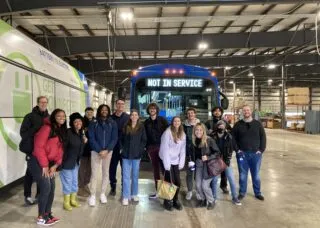 BAUSP seniors standing in a bus barn