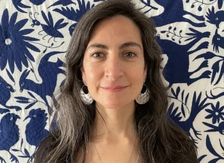 Photo of Daniela in front of a blue and white quilt