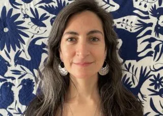 Photo of Daniela Morales Fredes in front of a blue and white floral quilt