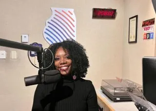 Ruby Mendenhall smiling at the camera with microphone in front of her.