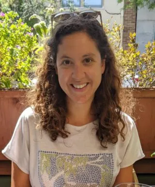 Photo of Irene Farah Rivadeneyra sitting outside in front of flowers