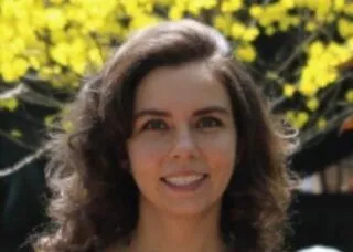 Photo of Julia Paiva in front of a yellow tree