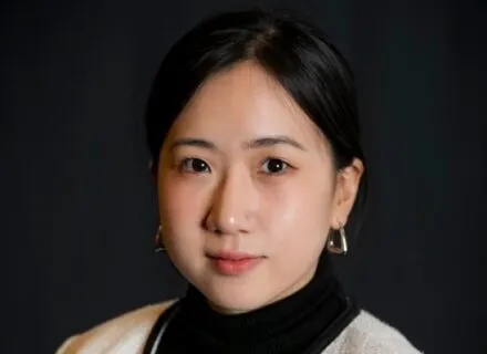 Photo of Nadia Kim in white blazer with a black background